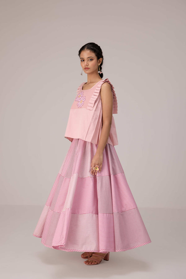 Soft pink sleeveless relaxed fit blouse with pleat details and hand embroidery paired with flared tiered patchwork maxi skirt
