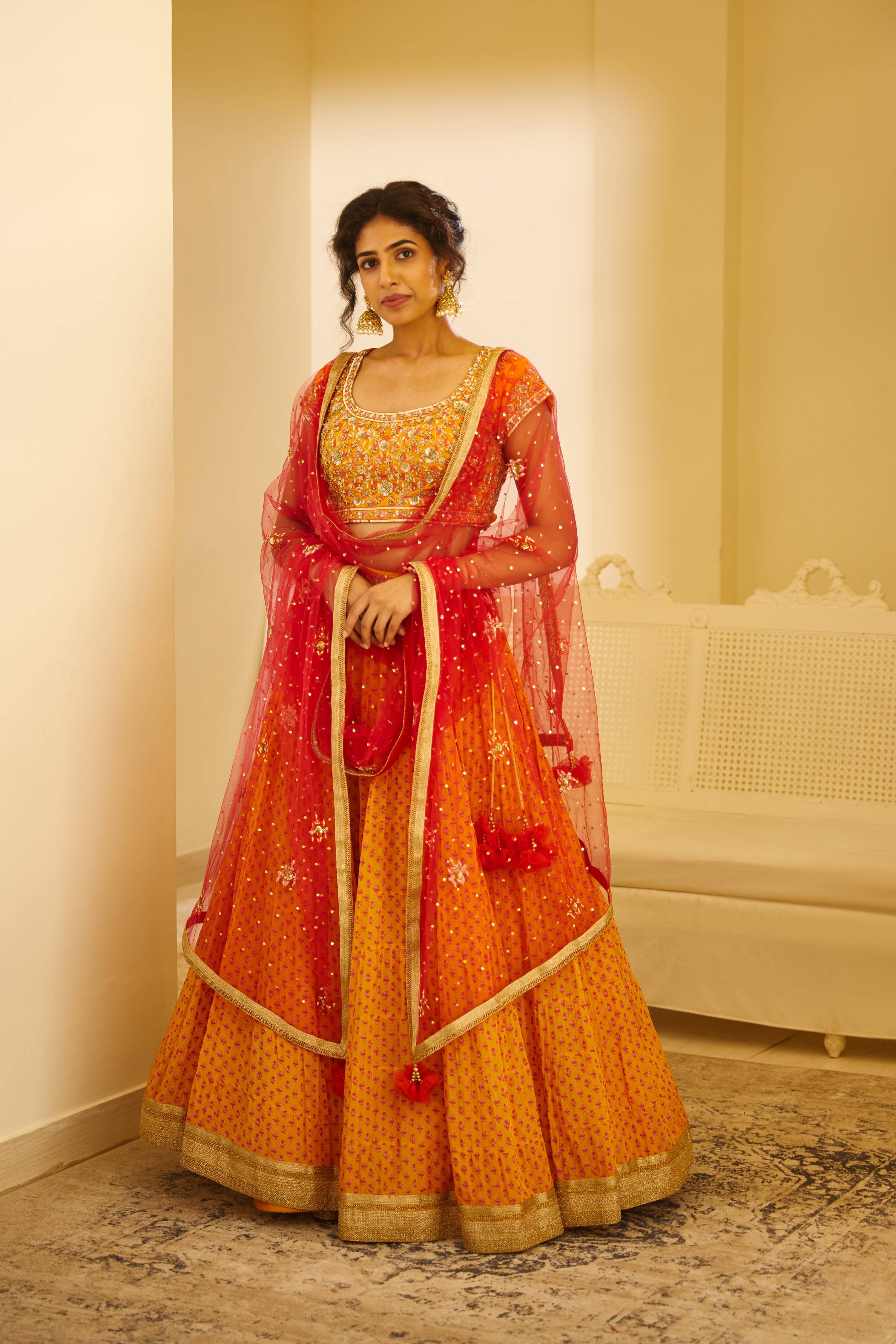 A bright red and orange lehenga complimented with a beautifully crafted  gotapatti work, this color combination looks graceful as… | Orange lehenga,  Lehenga, Fashion